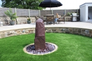 <h5>Plum slate Monolith</h5><p>A water feature sunk in the garden, in this beautiful landscape project</p>